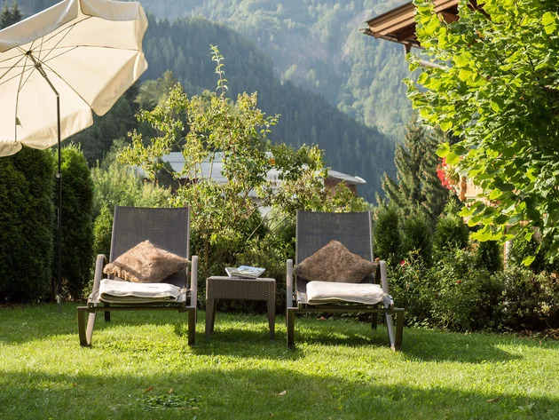 Zwei Liegestühle mit Kissen und Decken im Garten, Bergblick im Hintergrund