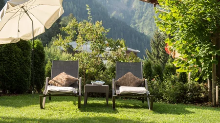 Zwei Liegestühle mit Kissen und Decken im Garten, Bergblick im Hintergrund