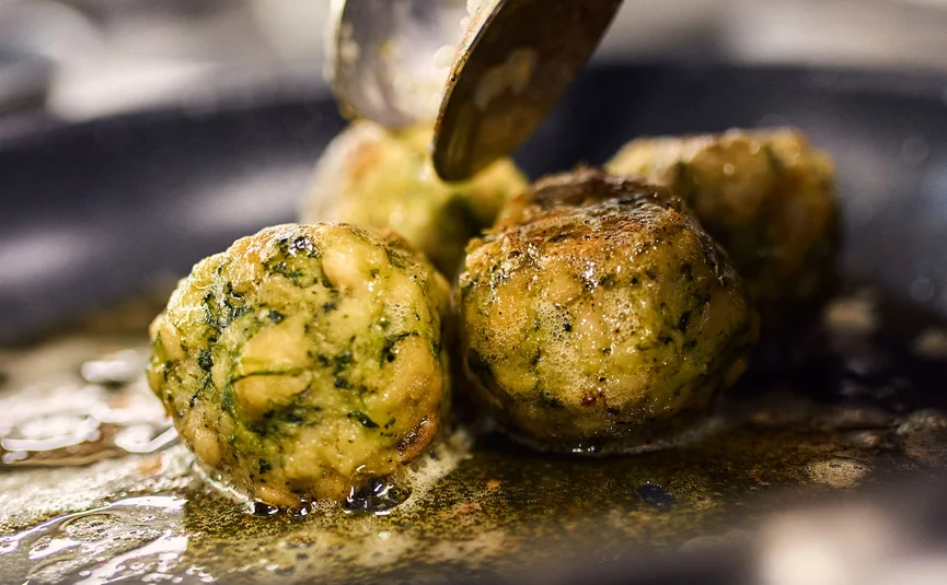 Spinach balls frying in a pan with oil