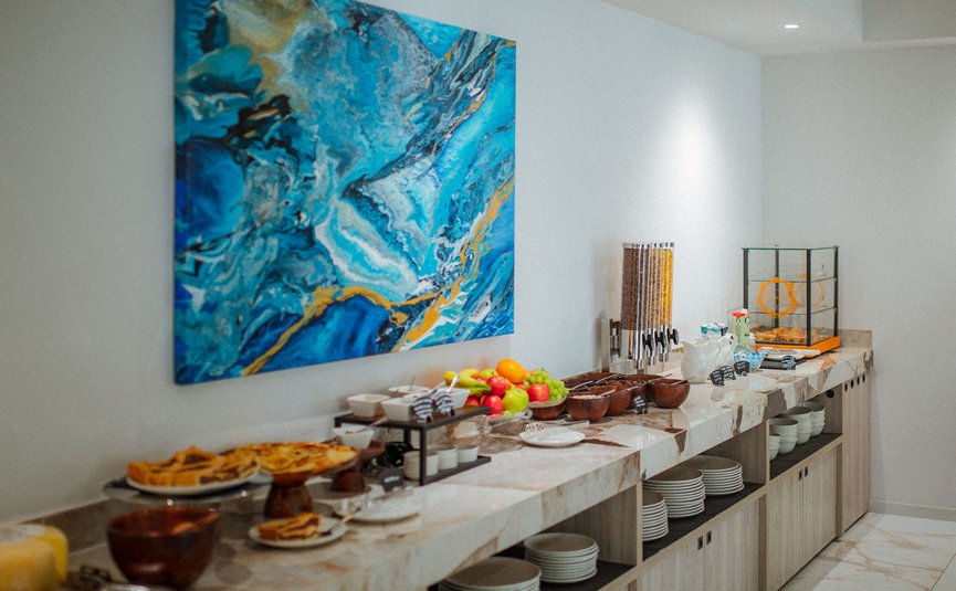 Buffet mit Obst, Gebäck und Müsli in modernem Raum mit blauem Gemälde
