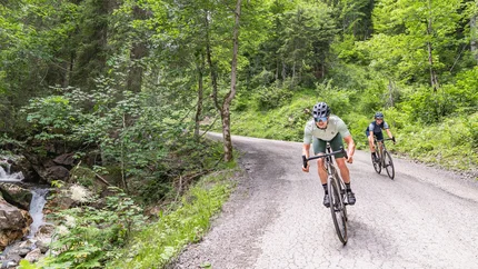 Zwei Radfahrer fahren auf einem Waldweg neben einem Bach