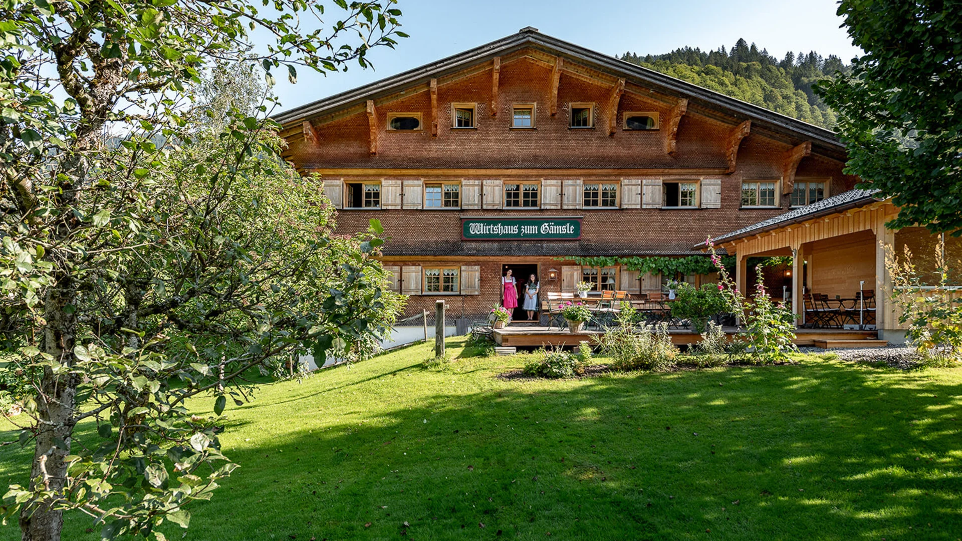 Traditionelles Gasthaus in einer grünen Landschaft mit zwei Personen an der Tür