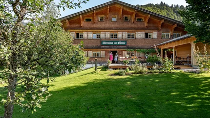 Traditionelles Gasthaus in einer grünen Landschaft mit zwei Personen an der Tür