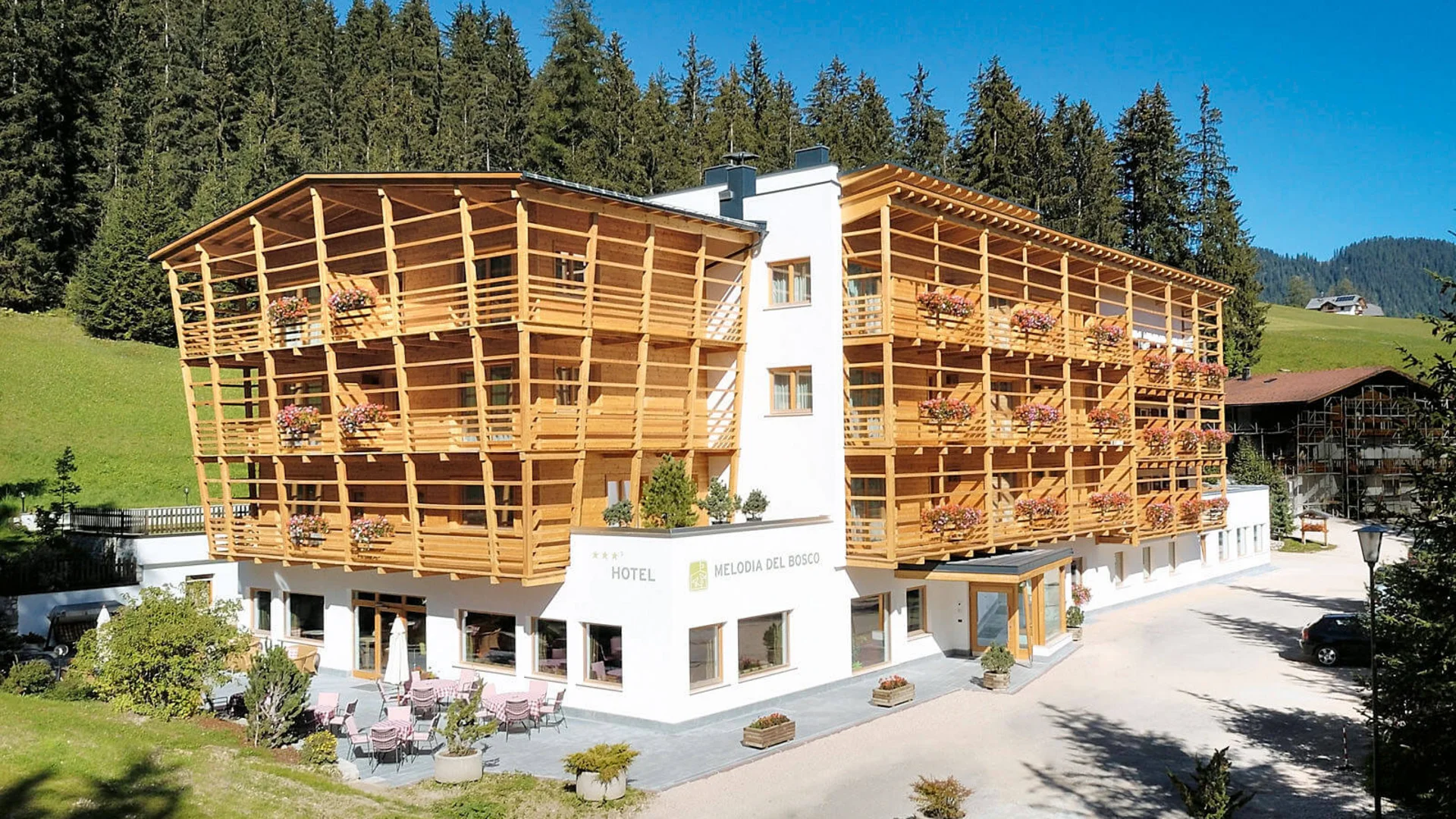 Hotel Melodia del Bosco mit Holzfassade in bergiger Waldlage
