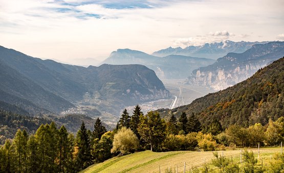 Blick auf bewaldete Berge und ein Tal unter bewölktem Himmel