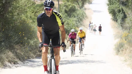 Cyclist in sportswear riding on a sunny forest path ahead of other cyclists