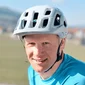 Nahaufnahme eines lächelnden Mannes mit weißem Fahrradhelm und blauem Shirt