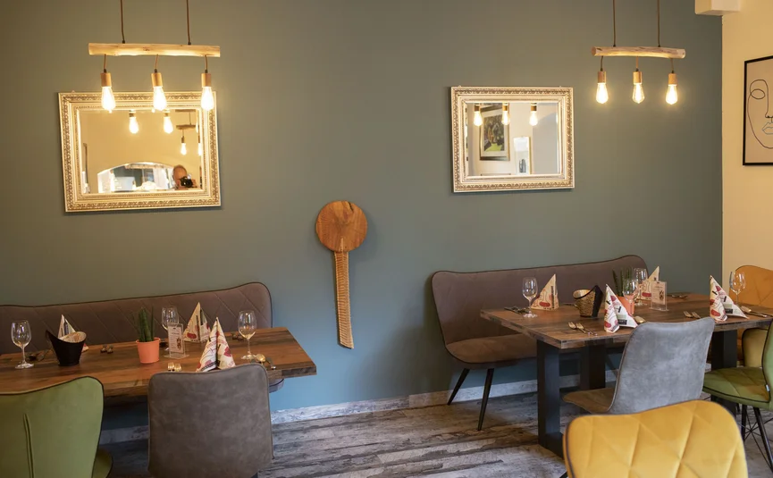 Cozy dining area with tables, chairs, mirrors, and hanging lights