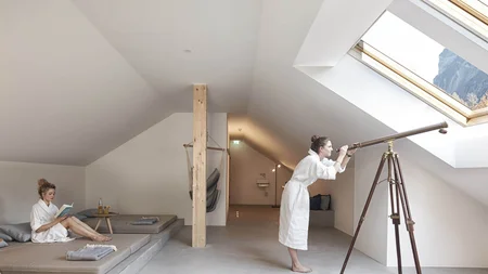 Müde Beine, volle Bäuche, offene Herzen © Hotel Bären - Cafe Deli Mellau Frau im Bademantel beobachtet mit Teleskop durch Dachfenster in modernem Raum