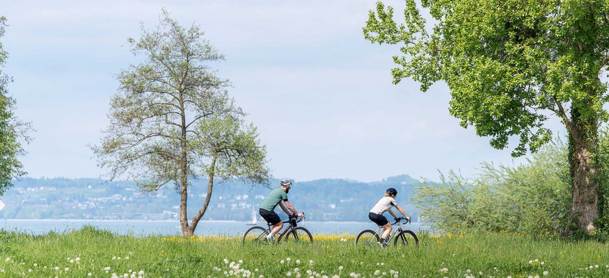Zwei Radfahrer fahren auf einem Weg am See entlang im Frühling