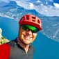 Man with red helmet taking selfie with mountains and lake background