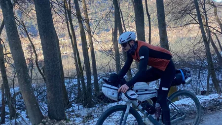Bikepacking von Wien nach Athen © Jan Koller Radfahrer auf einem Waldweg im Winter mit Bergen im Hintergrund