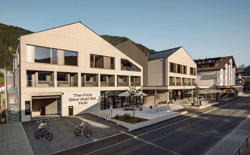 Modern building with bike and ski hub and two cyclists outside
