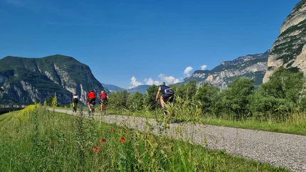 Cyclists riding on a path with mountains and blue sky in the background