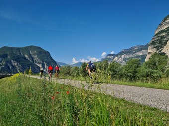 Radfahrer auf einem Weg mit Bergen und blauem Himmel im Hintergrund