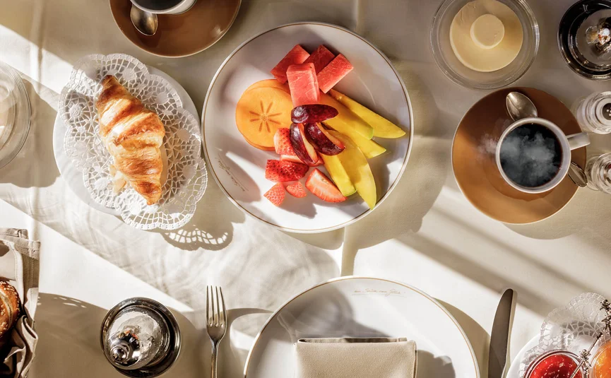 Frühstückstisch mit frischem Obst, Croissant und Kaffee