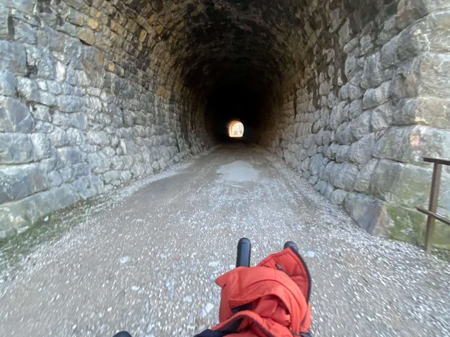 Bikepacking von Wien nach Athen © Jan Koller Blick von Fahrradlenker auf einen dunklen Steintunnel mit Licht am Ende