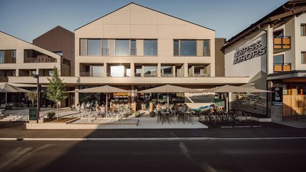 Exterior of Dips & Drops bistro with terrace and guests in sunlight