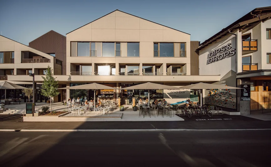 Dips&Drops - HOTEL · SPORTS · SPA · RESTAURANTS ****S © Matthias Warter Exterior of Dips & Drops bistro with terrace and guests in sunlight