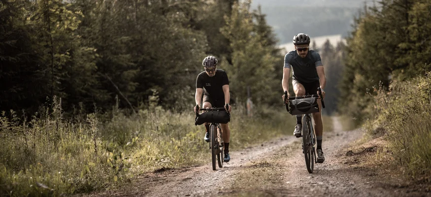 Graveln für Anfänger © Martin Matula Zwei Radfahrer fahren auf einem Waldweg bei bewölktem Himmel