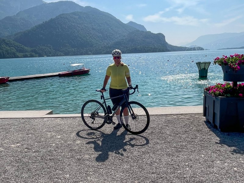 Fahrradfahrer am See mit Bergen im Hintergrund und klarem Himmel