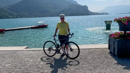 Fahrradfahrer am See mit Bergen im Hintergrund und klarem Himmel