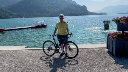 Fahrradfahrer am See mit Bergen im Hintergrund und klarem Himmel