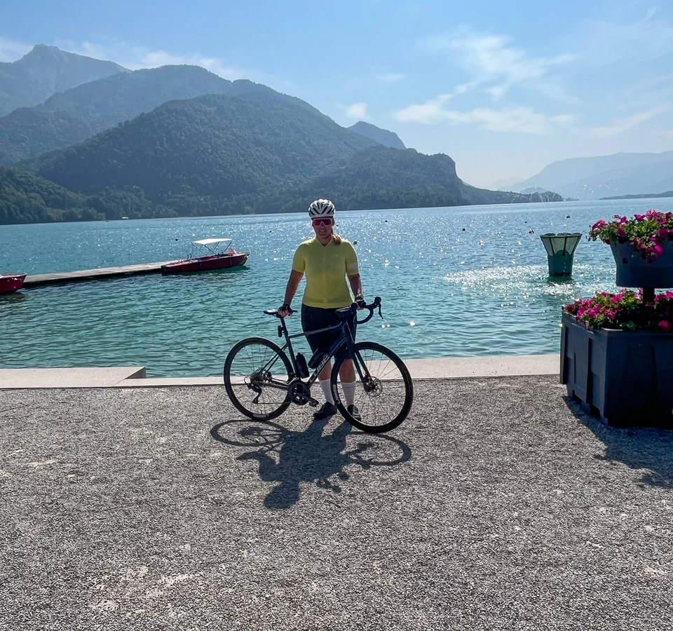 Fahrradfahrer am See mit Bergen im Hintergrund und klarem Himmel