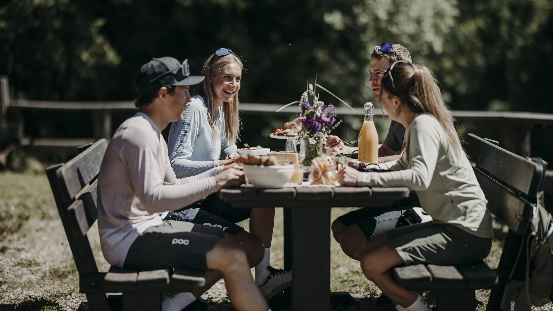5 Gravel-Touren in der Salzburger Sportwelt, die du kennen solltest © Matthias Warter Vier Personen sitzen draußen an einem Holztisch und essen im Sonnenschein