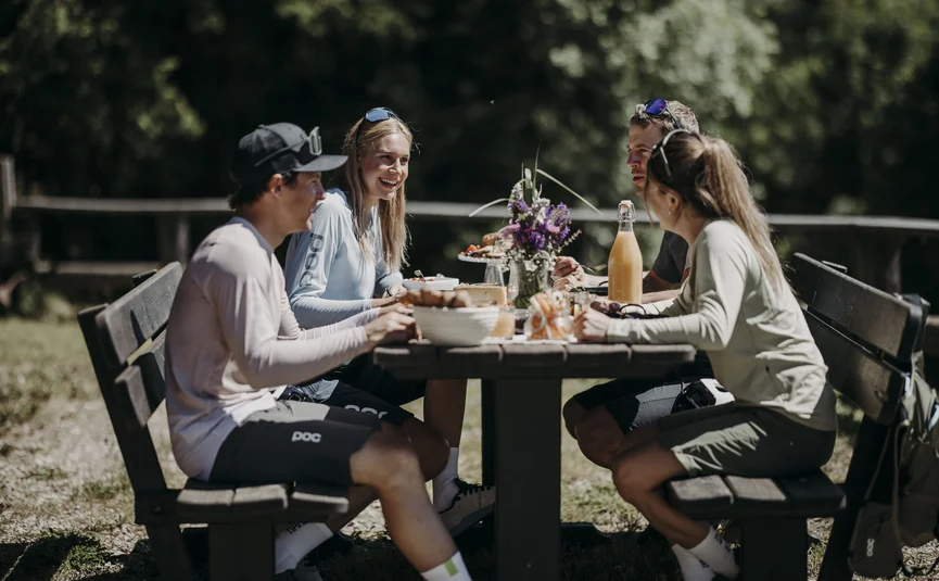 Dips&Drops - HOTEL · SPORTS · SPA · RESTAURANTS ****S © Matthias Warter Four people sitting outdoors at a wooden table eating in the sunshine