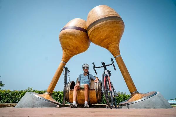 Slovenia Gravel Experience © Alain Rumpf Frau auf Schaukel unter riesigen Holzmaracas neben Fahrrad