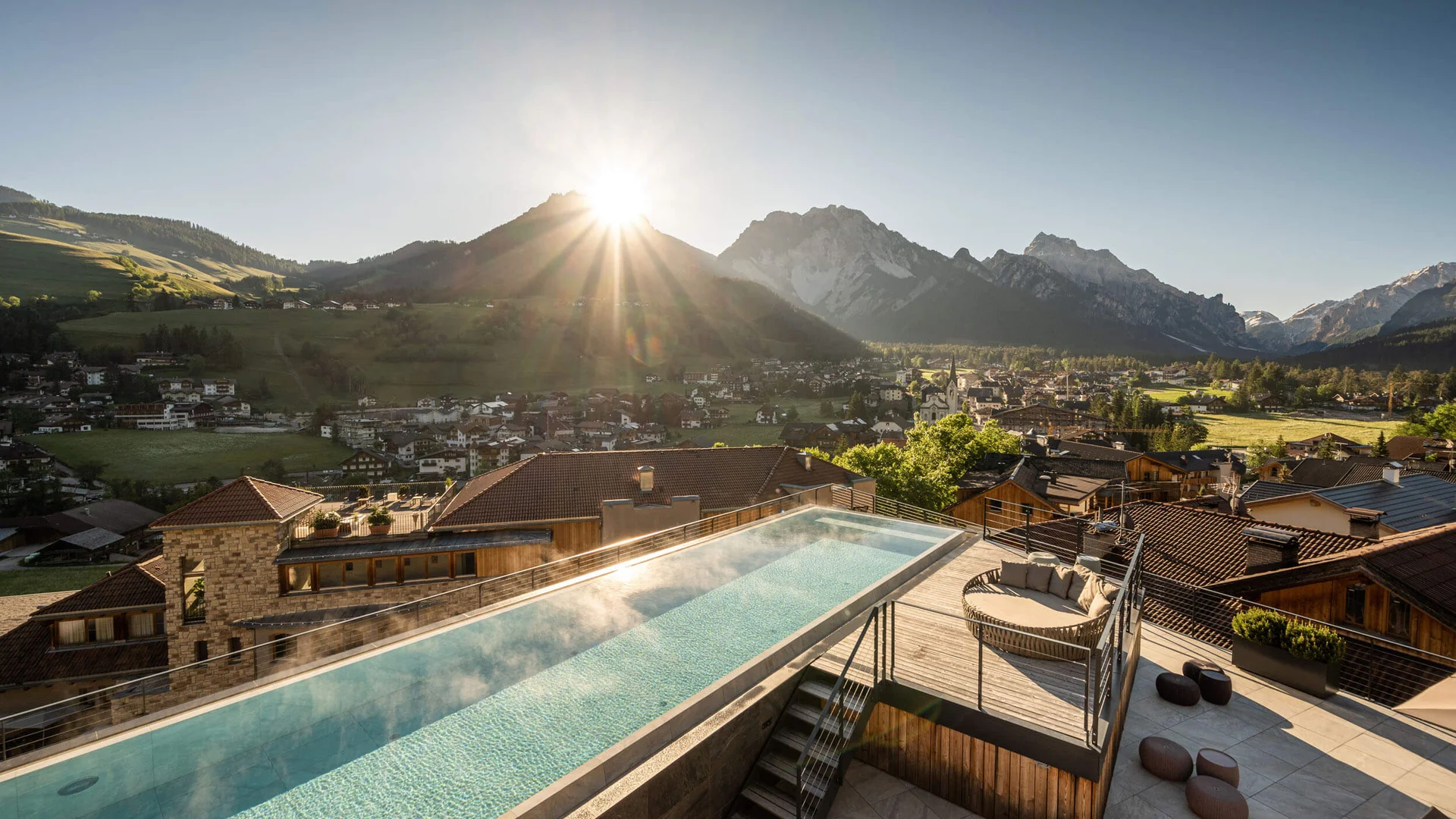 Sonnenaufgang über einem Bergdorf mit beheiztem Pool auf einer Terrasse