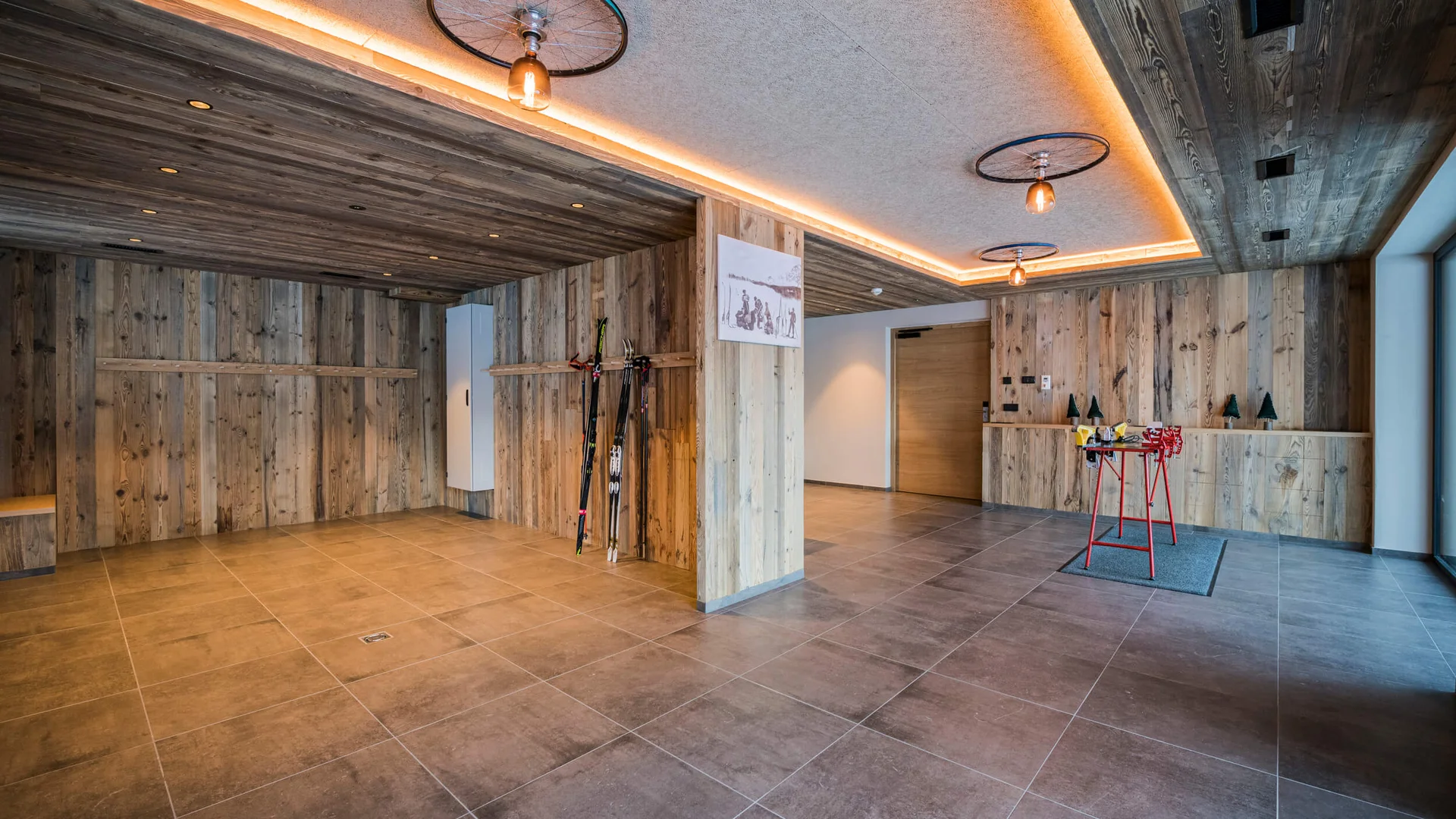 Geräumiger Raum mit Holzverkleidung, Skiern und Skistöcken an der Wand