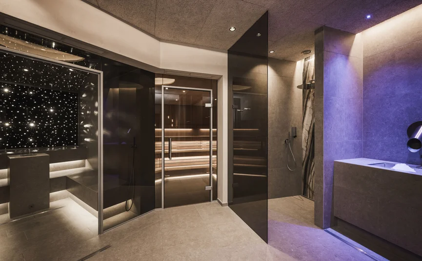 Modern spa area with sauna, steam bath, and warm and blue lighting