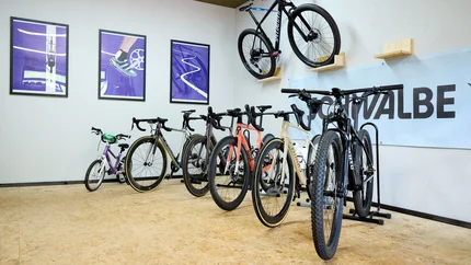 Multiple bicycles indoors, some hanging on the wall