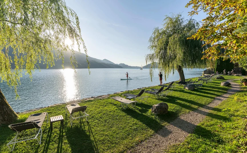 Sunny lakeside with lounge chairs and people on the water