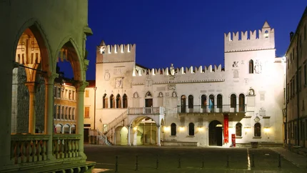 Historic illuminated building with arches and battlements at night