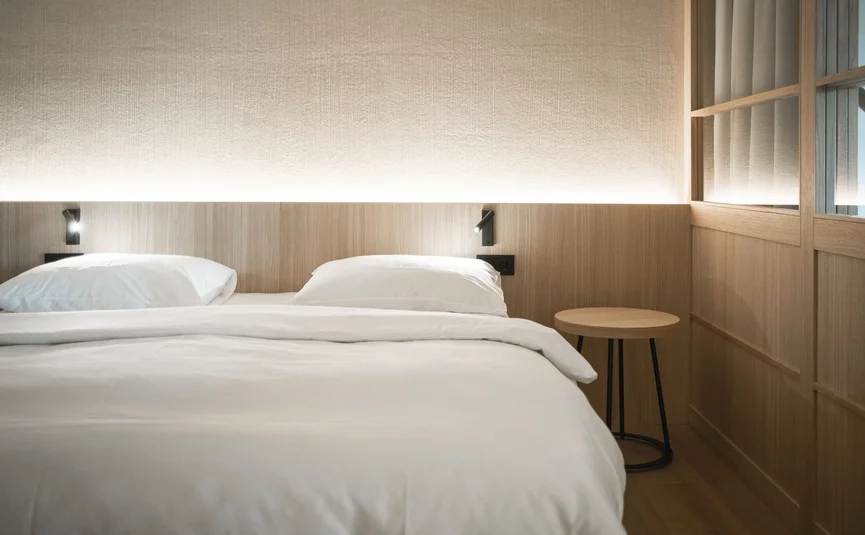 Minimalist bedroom with double bed and wooden wall paneling