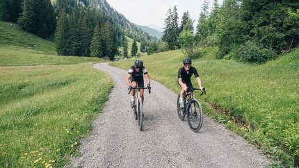 Bregenzerwald Gravel Tour © Ian Ehm - Vorarlberg Tourismus Two cyclists riding on a gravel path through a green mountain landscape