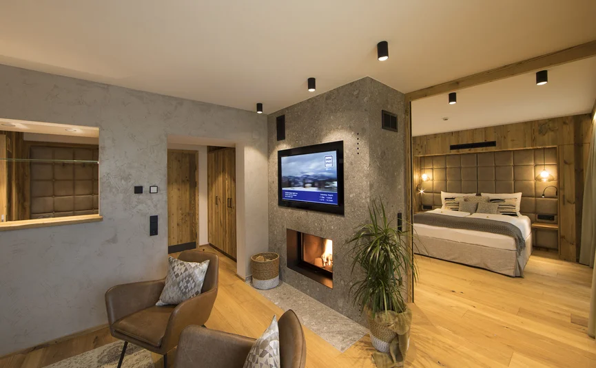 Aktivhotel Alpendorf **** © Atelier Oczlon Modernes Wohnzimmer mit Kamin und angrenzendem Schlafzimmer
