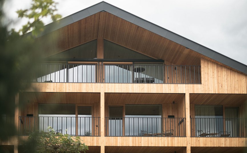 Gisse Zwölf **** © Lunah Photography - Lukas Haberer & Hannah Beikircher Moderne Holzhausfassade mit Balkonen und Glasfenstern bei bewölktem Himmel