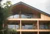 Modern wooden house facade with balconies and glass windows under cloudy sky