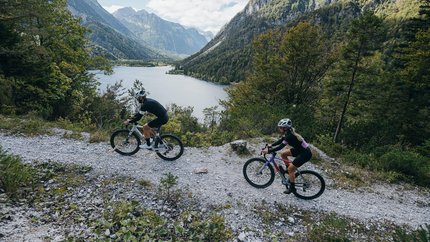Wörthersee © WRTG Fotograf Sam Strauss Zwei Radfahrer auf Bergweg mit See und Bergen im Hintergrund