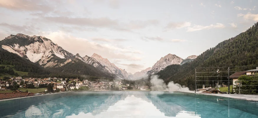 Infinity pool with mountain view and small village in the valley