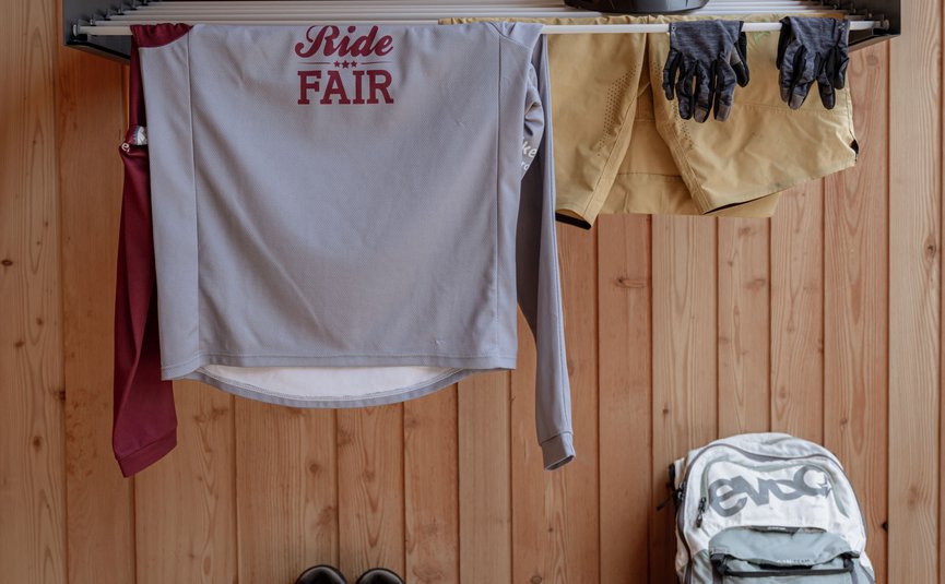 Gisse Zwölf **** © Ueberall Fahrradbekleidung, Helm, Schuhe und Rucksack vor Holzwand aufgehängt
