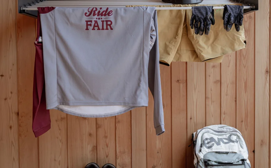 Bike clothing, helmet, shoes, and backpack hanging in front of wooden wall