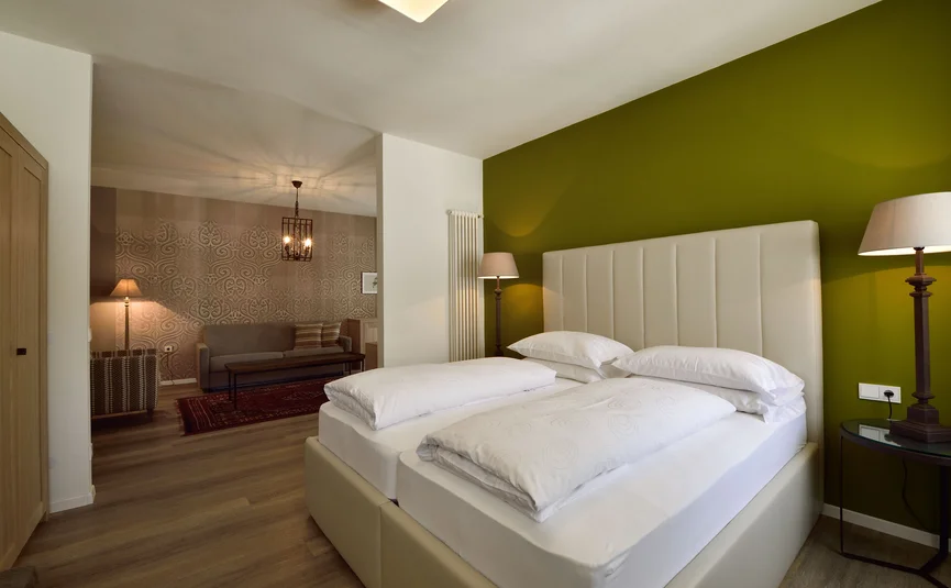 Modernes Schlafzimmer mit grünem Wandakzent und angrenzendem Wohnzimmer