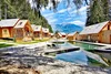 Wooden cabins by a lake with mountain view and lounge chairs on dock