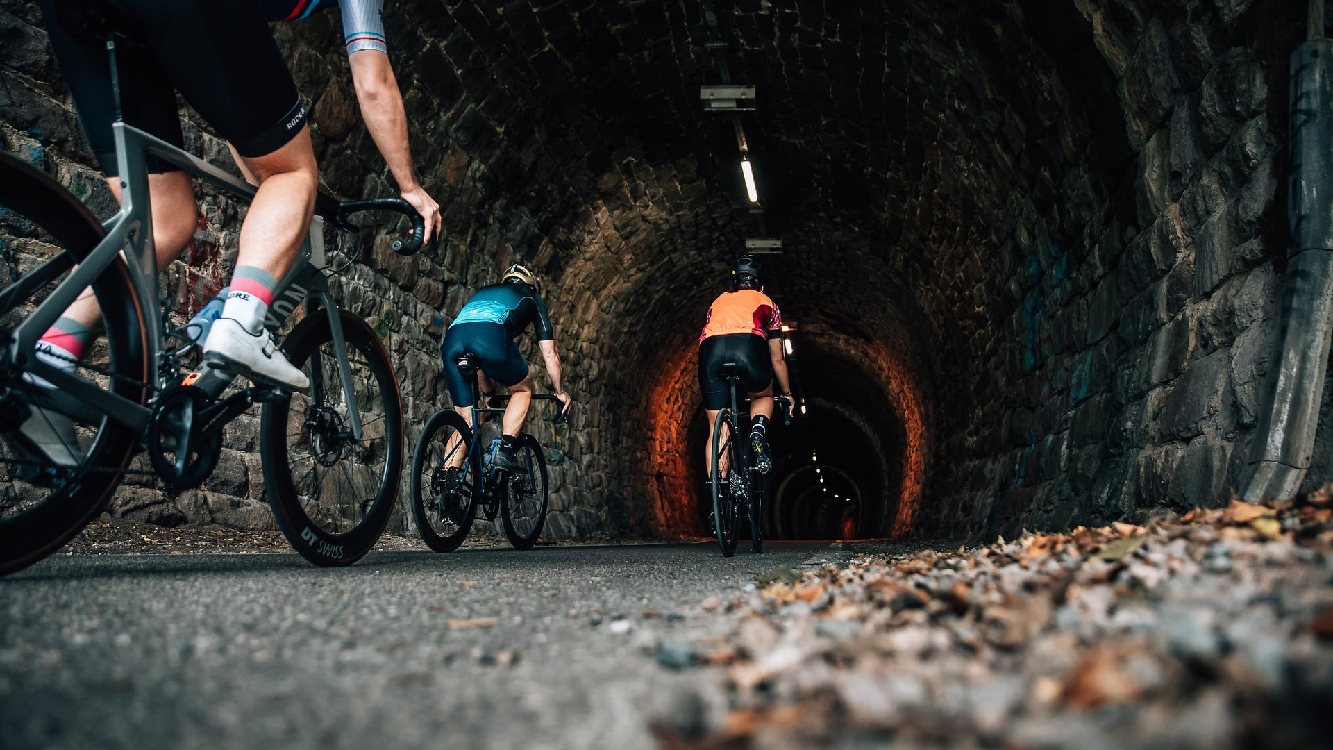 Radfahrer fahren durch einen beleuchteten Steintunnel auf der Straße