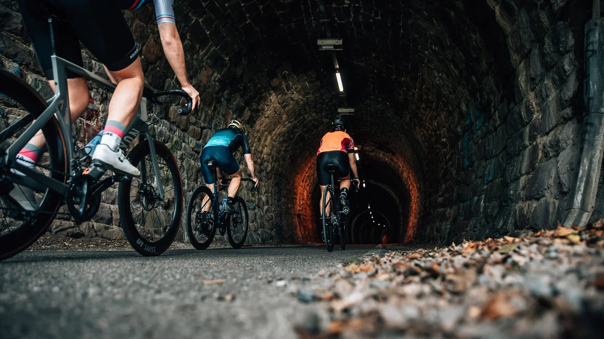 Genuss & Gravel in Tramin © Jens Scheibe Radfahrer fahren durch einen beleuchteten Steintunnel auf der Straße